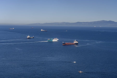 Multiple ships crossing the Strait of Gibraltar under clear blue skies and calm sea.