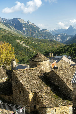 Rustic stone houses with slate roofs in the village of Fanlo, surrounded by lush green valleys and...
