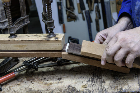 Luthier aligns and secures fretboard on classical guitar neck