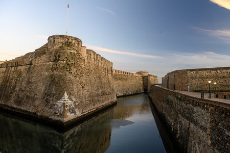 Massive stone bastions of the Murallas Reales in Ceuta reflected in a calm moat at dusk.の写真素材