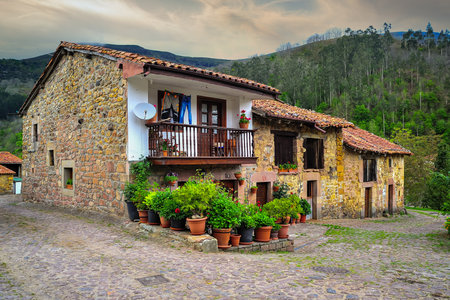 A charming stone house with a flowered balcony stands in the historic village of Carmona, accentuated by potted plantsの写真素材