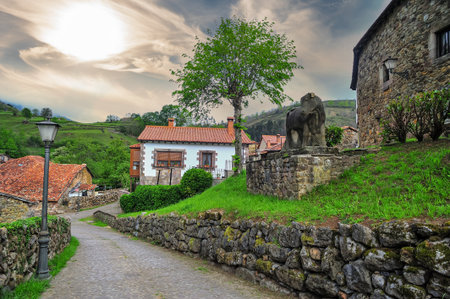 A cobblestone street in Carmona village, featuring a stone elephant sculpture and traditional houses against a dramatic skyの写真素材