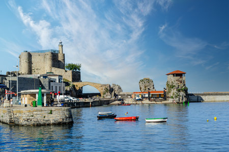 Sunny view of Castro Urdiales in Cantabria, featuring its iconic church and lighthouse by the harbor with boats.の写真素材