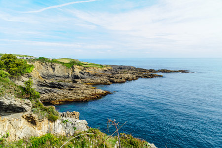 Striking layered rock formations along the rugged coast of Northern Spain with a clear blue sky overhead.の写真素材