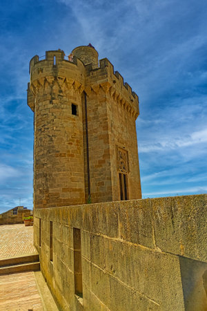 Ivy-covered medieval castle with stone towers, turrets, and walls, set against a vivid blue sky.の写真素材