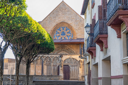 Gothic church facade with intricate stone arches, sculptures, and detailed carvings under a blue sky.の写真素材
