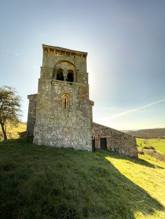 Historic Romanesque church with stone walls, red tile roof, and bell tower nestled in Palencia countryside.の写真素材