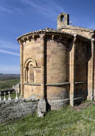 Historic Romanesque church with stone walls, red tile roof, and bell tower nestled in Palencia countryside.の写真素材