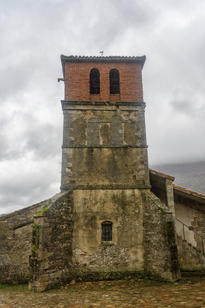 Old church with stone and brick architecture featuring a prominent bell tower in a rural village.の写真素材