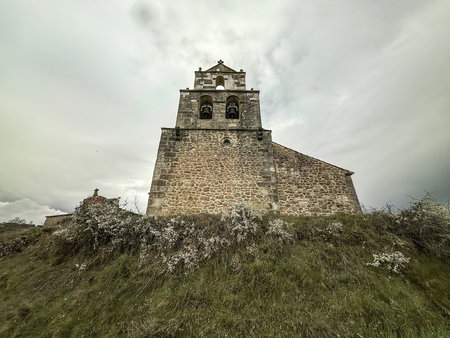 Tall stone bell tower of a historic church rising above hillside vegetation.の写真素材