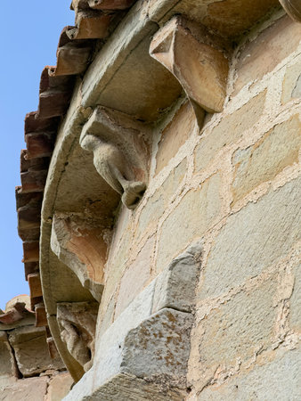 Detail of sculpted corbels with faces and spiral motif on Romanesque church wallの写真素材