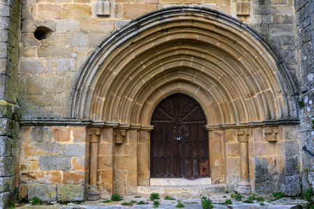 Stone entrance with semicircular archivolts and dark wooden door in Spanish churchの写真素材