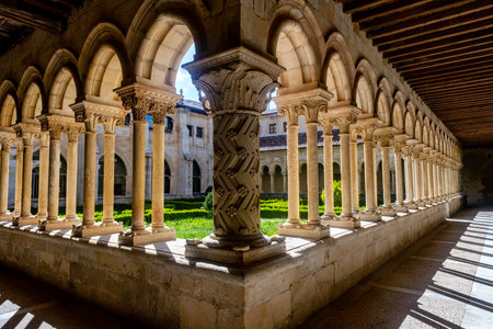 Peaceful medieval cloister with arches and carved capitals surrounding a lush central gardenの写真素材