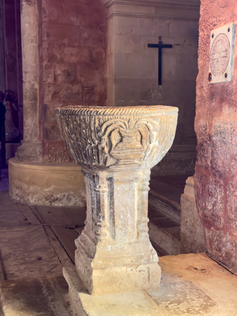 Medieval stone baptismal font with carved decorations in rural Spanish churchの写真素材