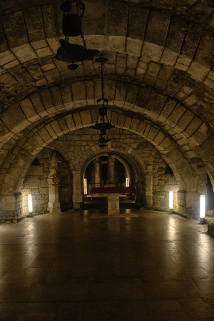 Ancient stone crypt with semicircular arches and dim lighting inside Palencia Cathedral, Spain