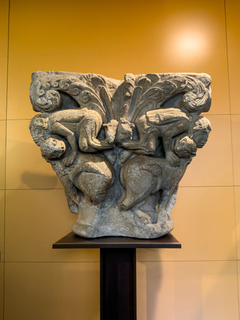 Ornate Romaneseque capital with sculpted figures and decorative foliageの写真素材