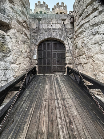 View of a raised wooden drawbridge and arched gate of a medieval stone castleの写真素材