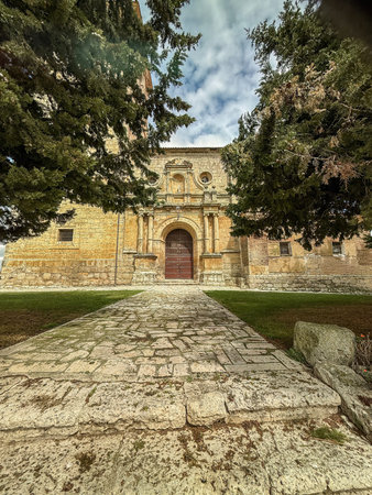 Large historic church with clock tower and strong buttresses in a Castilian village square