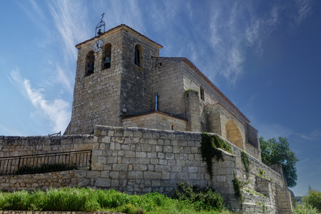 Stone church with bell tower and clock on a raised platform in Cobos de Cerratoの写真素材