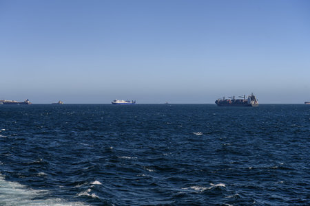 Port of Algeciras with ferries, cargo ships, cranes, and storage tanks under blue sky.の写真素材