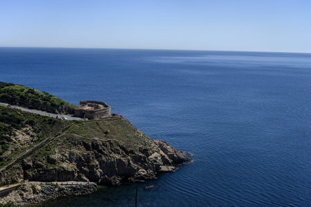 Stone fort of Desnarigado on a rocky cliff in Ceuta facing the calm blue sea.の写真素材