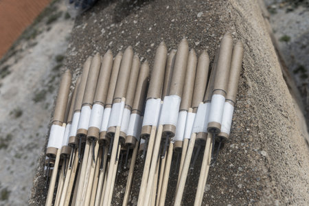 Bundle of cylindrical fireworks rockets with wooden sticks on a rough surfaceの写真素材