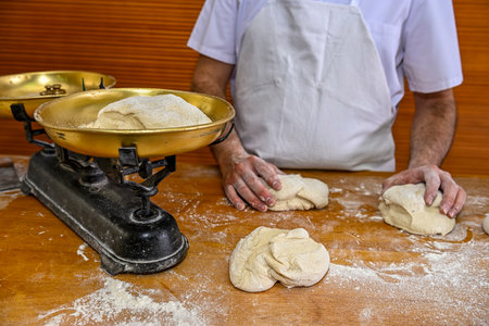Baker kneading artisan bread in the bakeryの写真素材