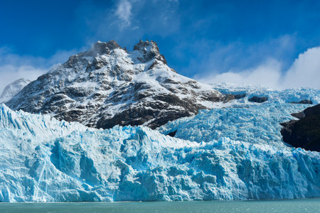 Massive Spegazzini Glacier meeting turquoise waters beneath rugged Patagonian peaksの写真素材