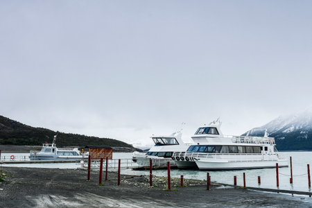 Passenger boats at the pier of Lago Argentino with snow-covered mountains in the backgroundの写真素材