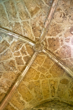 Detailed view of Romanesque vaulted ceiling with intersecting stone ribs and textured surface.の写真素材