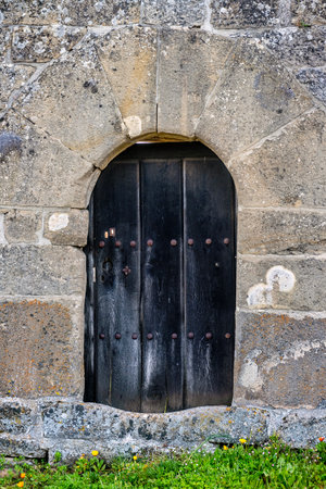 Weathered wooden door set in stone archway of historic rural church in Villanueva de Henaresの写真素材