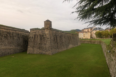 The Fortaleza de Jaca, a historic citadel featuring stone walls, a bell tower, and lush green lawns,...