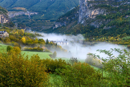 Charming view of Torla village nestled in a lush valley, surrounded by dramatic cliffs and snow-capped peaks.の写真素材