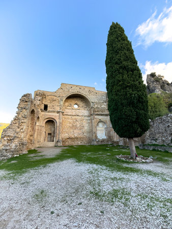 Historic church remains with arched structure and cypress tree in a serene settingの写真素材