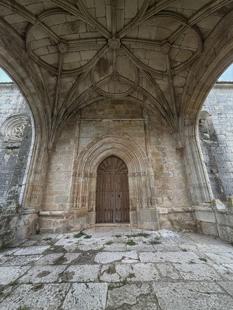 Detailed view of the Gothic stone doorway and vaulted porch of Iglesia de San Fructuoso in Palencia.
