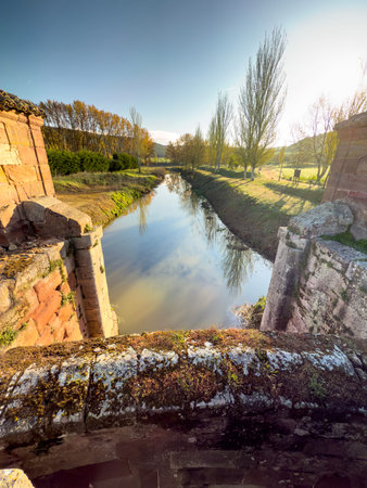 Ancient lock system of Canal de Castilla in Alar del Rey reflecting on calm waterの写真素材
