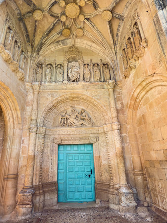 Intricately carved stone portal with biblical figures above a turquoise wooden doorの写真素材