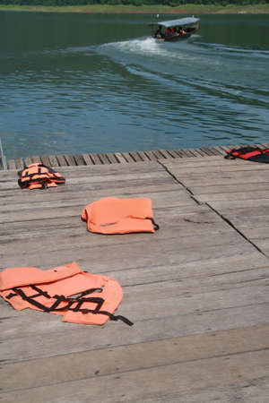life vest on wood floor with a boat on river background の写真素材