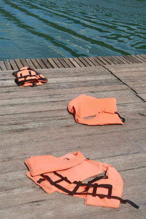 life vest on wood floor with a boat on river background の写真素材
