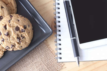 chocolate chip cookie with pen and notebookの写真素材