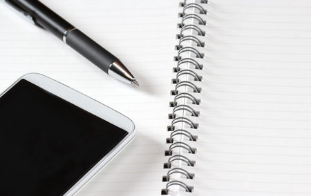 Close up shot of hand held calculator, silver pen and notepad in horizontal layout
