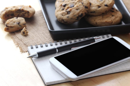 notebook on desk with coffee biscuit and pen, home office concept