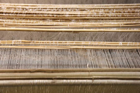 Close up of gold silk weaving on wooden loomの写真素材