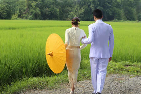 couple of women and man with Thai traditional dress walking on path on rice field, Chiang Mai, Thailandの写真素材
