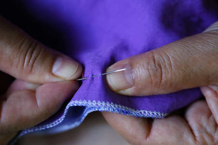 closeup women hand sewing on purple fabric, needleの写真素材