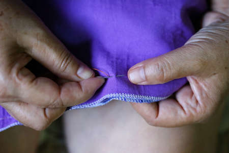closeup women hand sewing on purple fabric, needleの写真素材