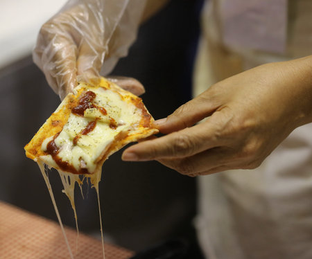 hand hold piece of baked pizza
