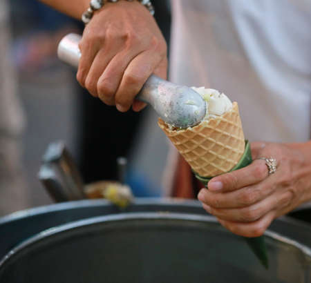 hand with ice cream scoop on cones , Thailandの写真素材