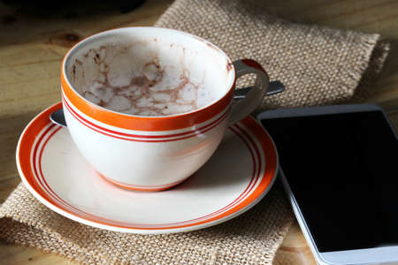 Empty coffee cup and smartphone in cafeの写真素材