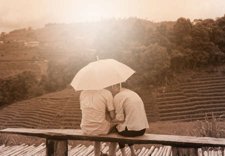 lover with umbrella sit on bench, northern thailandの写真素材